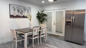 A dining area with a table, chairs, a vase with flowers, a ceiling fan, and a refrigerator. - Recently Updated, King bed, Near U of A & Downtown (Springdale)