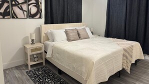 A bedroom with a bed, nightstand, lamp, and artwork on the wall. - Recently Updated, King bed, Near U of A & Downtown (Springdale)