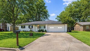 A single-story house with a front garage, a mailbox, and a well-maintained lawn. - Recently Updated, King bed, Near U of A & Downtown (Springdale)