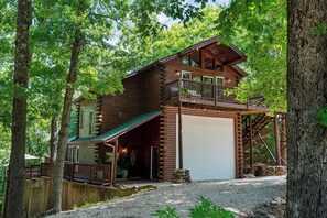 A two-story log cabin with a balcony, a garage, and a covered porch. - Cabin 6 Minutes From Silver Dollar City, Sleeps 6 (Branson)