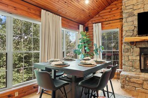 A dining area with a wooden table, chairs, and a stone fireplace. - Cabin 6 Minutes From Silver Dollar City, Sleeps 6 (Branson)