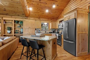 Eine Holz-Küche mit einer zentralen Kochinsel, Barhocker und einem Kühlschrank.