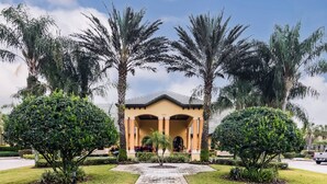 A building with a central entrance, surrounded by well-maintained landscaping and palm trees. - Golden Hours at Paradise Palms (Kissimmee)