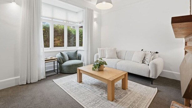 A modern living room with a sofa, a round armchair, a wooden coffee table, and a hanging light fixture. - Dellara Cottage Retreat (North Hobart)