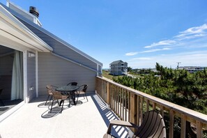 Ein Balkon mit Tisch und Stühlen, einem Hollerleger und Blick auf eine Wohngegend mit Häusern und Bäumen.
