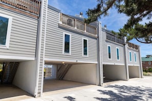 En tvåvåningsbyggnad med en inglasad veranda, ett garage och en trappa som leder upp till övre våningen.