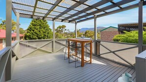 Ett takförsett utomhusområde med ett bord och stolar, utsikt över det omgivande landskapet och en pergola.