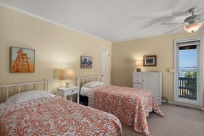 Ein Schlafzimmer mit zwei Betten, einem Nachttisch, einer Kommode, einem Deckenventilator und einem Fenster mit Blick.