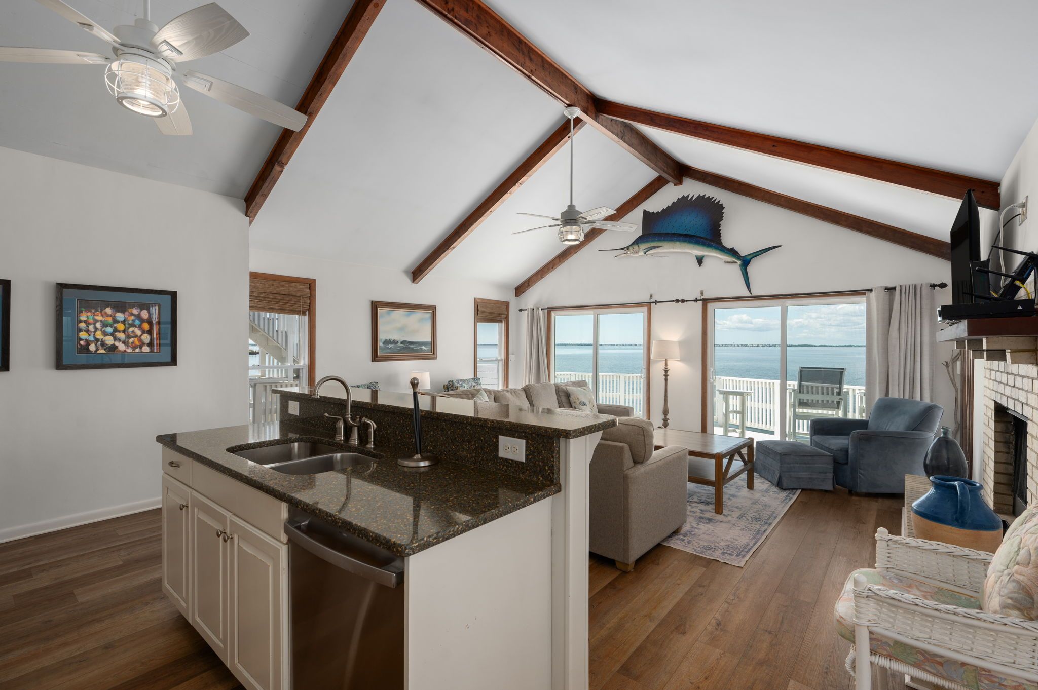 A spacious living area with a kitchen island, a ceiling fan, and a large fish decoration.