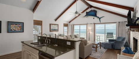 A spacious living area with a kitchen island, a ceiling fan, and a large fish decoration.