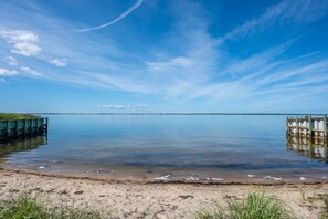 Ein ruhiger See mit einem hölzernen Steg, der ins Wasser führt, umgeben von einem Sandstrand.