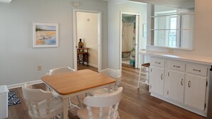 Cocina con armarios blancos, una mesa de madera y sillas.