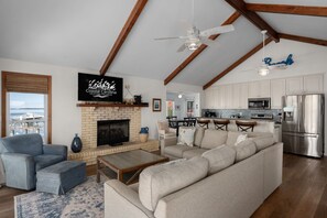 Ein Wohnzimmer mit Kamin, einer Couch, einem Fernseher und Blick ins Freie.