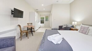 A hotel room with a bed, a desk, a chair, a TV, and a view of the outdoors.