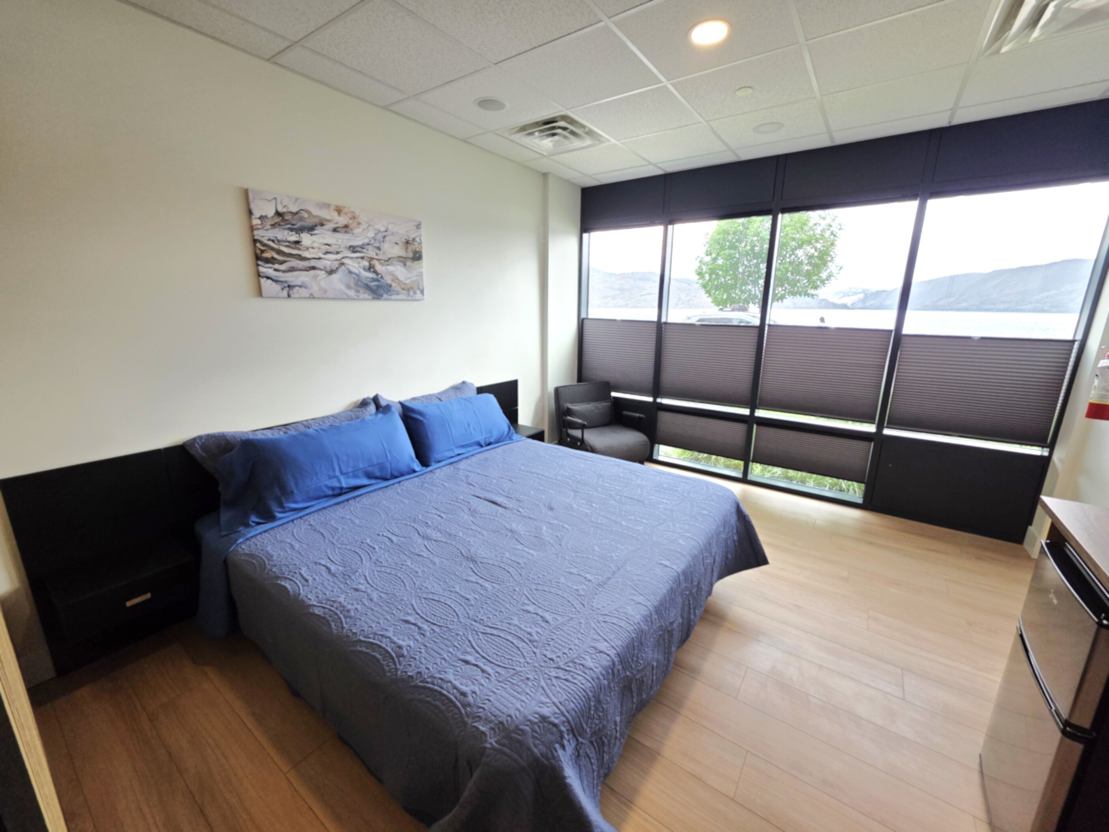 A modern hotel room with a large bed, a small seating area, and a window with a view of the outdoors.