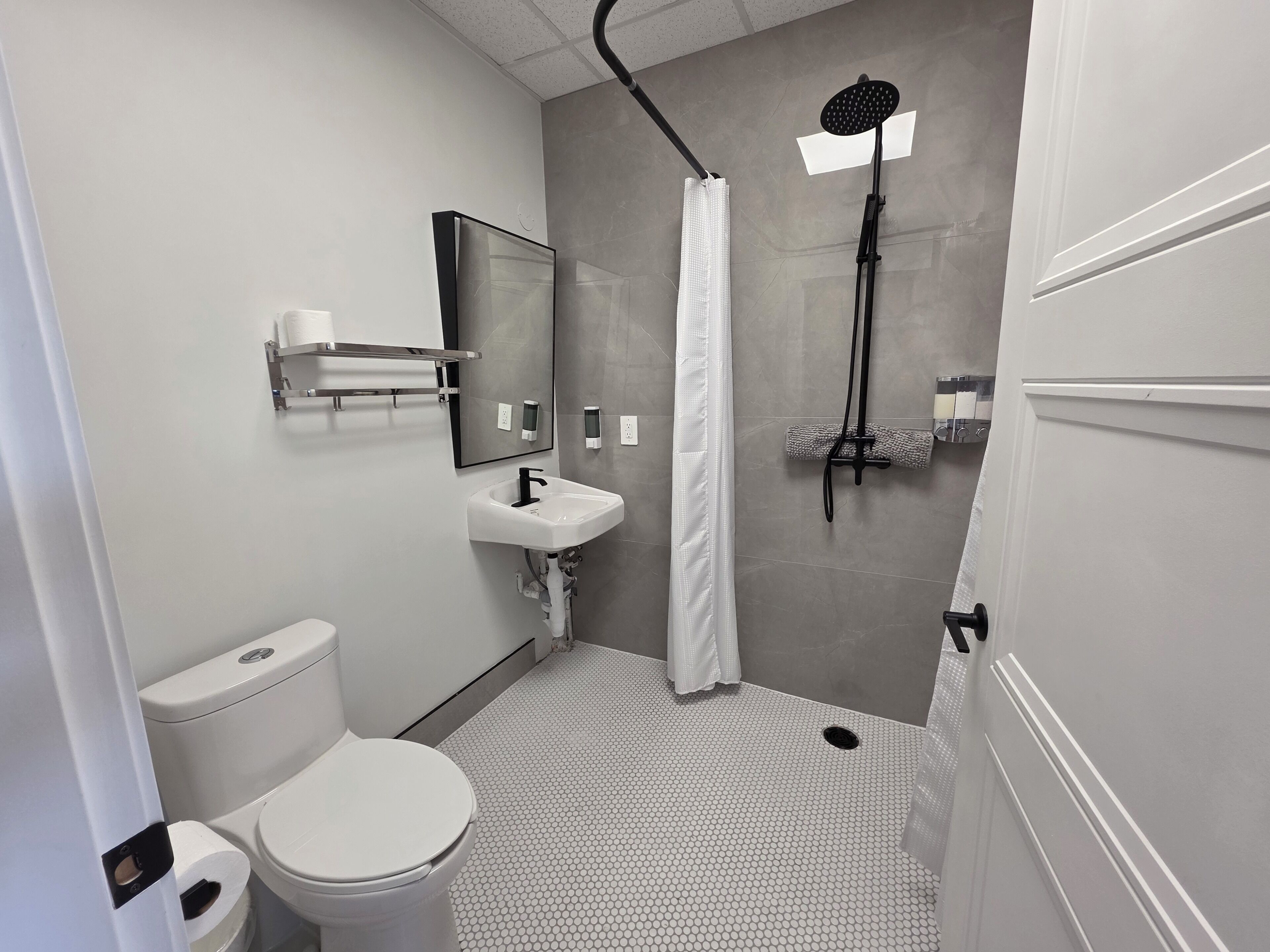 Une salle de bain moderne équipée de toilettes, d’un lavabo, d’une douche et d’un miroir.