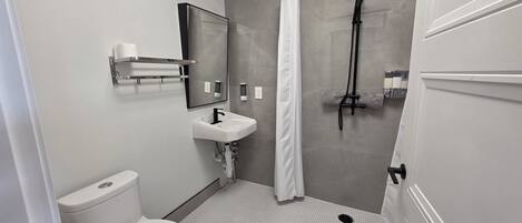 Une salle de bain moderne équipée de toilettes, d’un lavabo, d’une douche et d’un miroir.