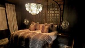 A bedroom with a large bed, a chandelier, and a wooden headboard. - Bougie Basecamp: Heated Pool+Hot Tub+Sauna+Trails+Adventure Toy Rental Options (Lehi)