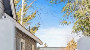 Een woonhuis met een oprit van beton, leidend naar een houten omheining en een gevel met donkere beplating.