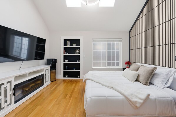 A modern bedroom with a large bed, a TV, a built-in shelf unit, and a window. - Cozy King Bed, Private Bathroom and Entryway (Bend)