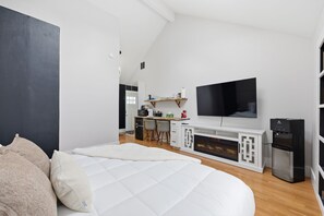 A modern bedroom with a large bed, a small kitchenette, a flat-screen TV, and a water dispenser. - Cozy King Bed, Private Bathroom and Entryway (Bend)