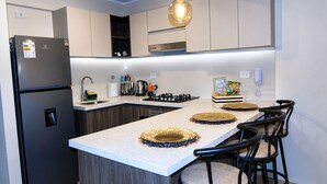 A modern kitchen with a central island, black appliances, and bar stools. - Brand-new apartment in the heart of Lima + fully furnished (Jesús María)