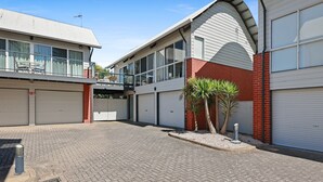 A building with multiple garage doors, a brick facade, and a flat roof. - 2/16 Flinders Pde, Victor Harbor (Victor Harbor)