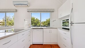 Eine moderne Küche mit weißen Schränken, einem eingebauten Ofen und einem Fenster mit Blick auf Bäume.