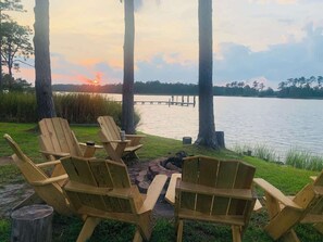 Un espacio de descanso junto al lago con sillas de madera y un brasero.