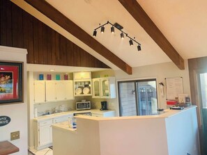 A kitchen with white cabinets, a microwave, and a refrigerator. There is a sign on the wall that says 'Love Wife.'