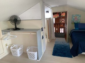 Une chambre avec un lit, un ventilateur, une armoire et un petit balcon.