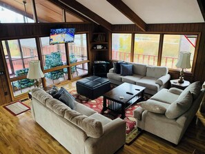 A spacious living room with a large window, a flat-screen TV, and a fireplace.