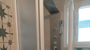Cabina de ducha con ducha de lluvia, ducha de mano y manguera para ducha de mano.