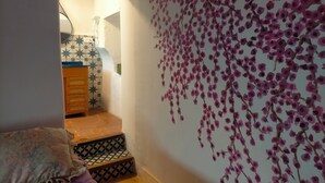 Una habitación con un papel tapiz estampado, una escalera y una cama.