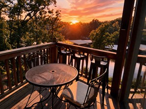 A wooden deck with a round table and chairs, overlooking a body of water and trees. - Canopy Seven: Tree Top - Pools - Pickleball - near Golf (Lake Ozark)