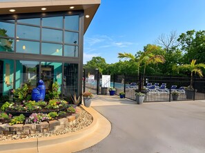A modern building with large windows, a pool area with lounge chairs, and a well-maintained garden with various plants. - Canopy Seven: Tree Top - Pools - Pickleball - near Golf (Lake Ozark)