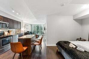 A modern kitchen with dark wood cabinets, stainless steel appliances, and a central island with seating. - The Vine & View Suite (Toronto)