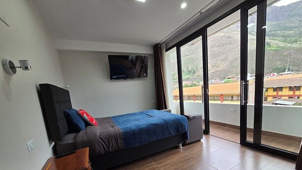A bedroom with a bed, a TV, a window, and a view of a mountain. - DIEGUITO'S HOUSE IN THE SACRED VALLEY (Cusco)