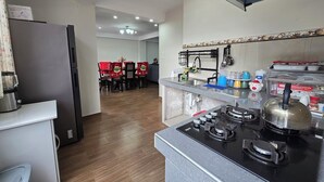 A modern kitchen with a gas stove, a refrigerator, and a dining area in the background. - DIEGUITO'S HOUSE IN THE SACRED VALLEY (Cusco)