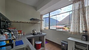 A kitchen with a large window, a sink, a stove, and a trash bin. - DIEGUITO'S HOUSE IN THE SACRED VALLEY (Cusco)