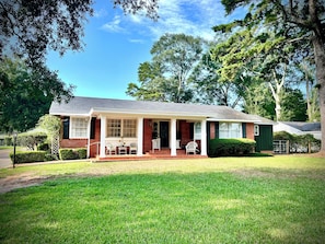 A two-story house with a front porch, brick exterior, and a well-maintained lawn.