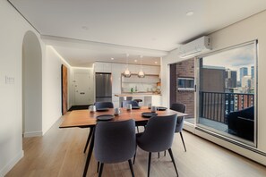 Een moderne keuken met een eethoek, grote ramen en uitzicht over de stad.