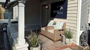 Eine überdachte Veranda mit einem Korbensofa, Blumentöpfen und einem dekorativen Wandbild.