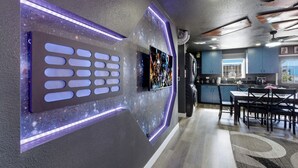 Une cuisine moderne dotée d’un grand îlot central, de meubles de rangement aux couleurs sombres et d’un coin repas avec une table et des chaises.