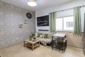 Ein modernes Wohnzimmer mit Steinwand, einer Couch, einem Couchtisch, einem kleinen Tisch mit Stühlen, einer Uhr und einem gerahmten Bild.