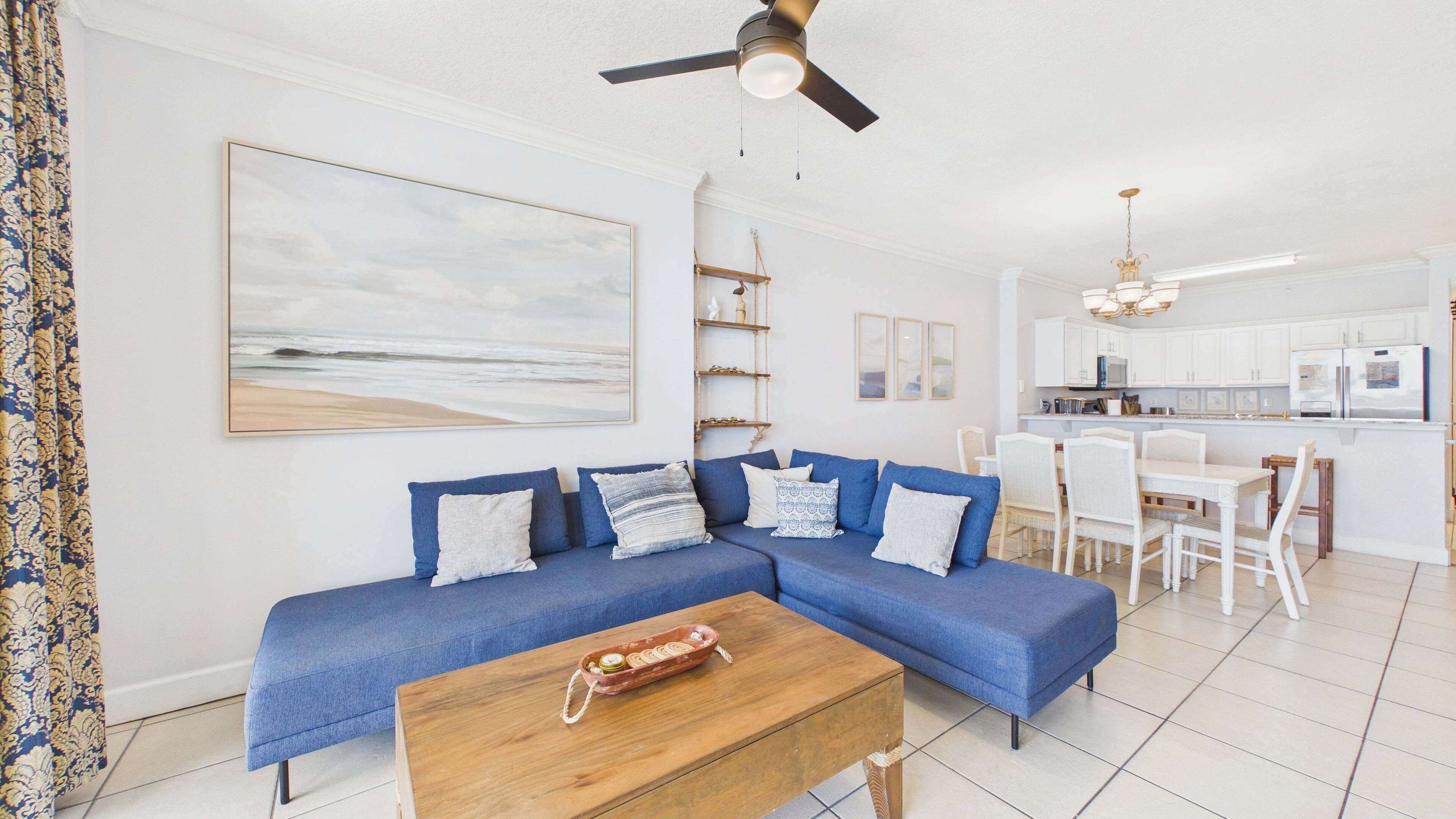 A living room with a blue sofa, a wooden coffee table, and a ceiling fan.