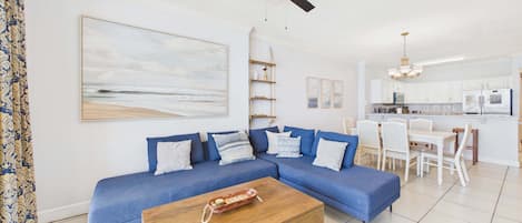 A living room with a blue sofa, a wooden coffee table, and a ceiling fan.