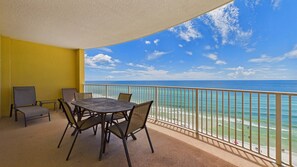 A balcony with a table and chairs, overlooking a beach and ocean. - Sunset Tides 1208-Gulf Front Balcony-Sleeps 6 (Panama City Beach)