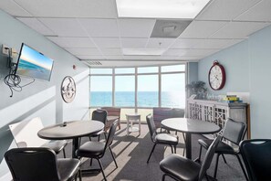 A conference room with a large window, a clock, a TV, and a 'Welcome' sign. - Sunset Tides 1208-Gulf Front Balcony-Sleeps 6 (Panama City Beach)