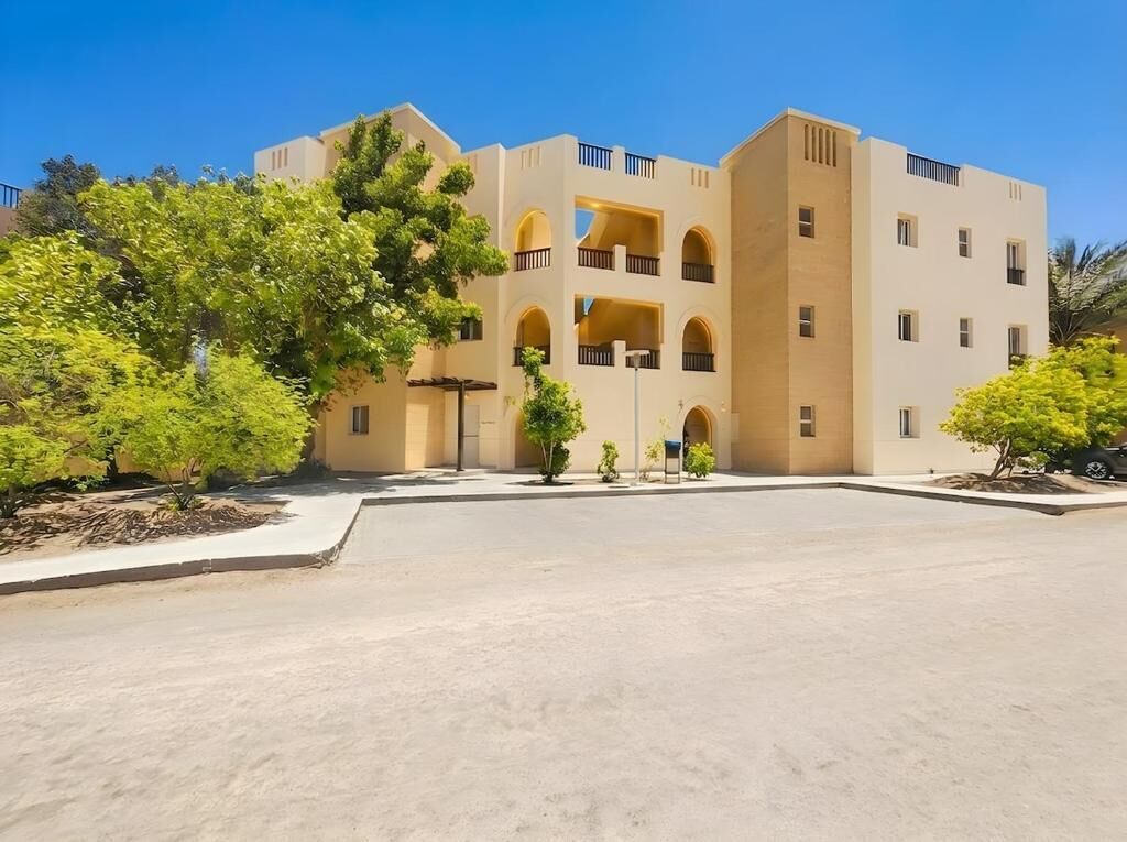 A multi-story building with a central courtyard, balconies, and greenery.